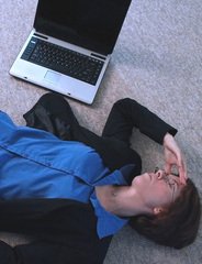 woman lying on the floor, her face in her hands beside a laptop