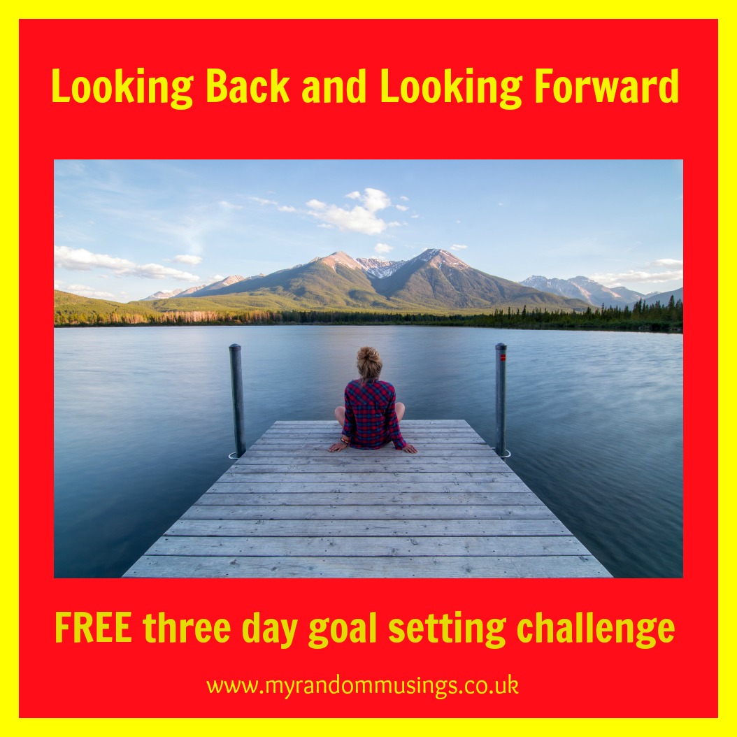 Looking Back and Looking Forward - FREE Three Day Goal Setting Challenge in yellow text on a red background with a yellow border. In the centre, a girl sits on the end of a pier looking out to the water with a mountain in the background