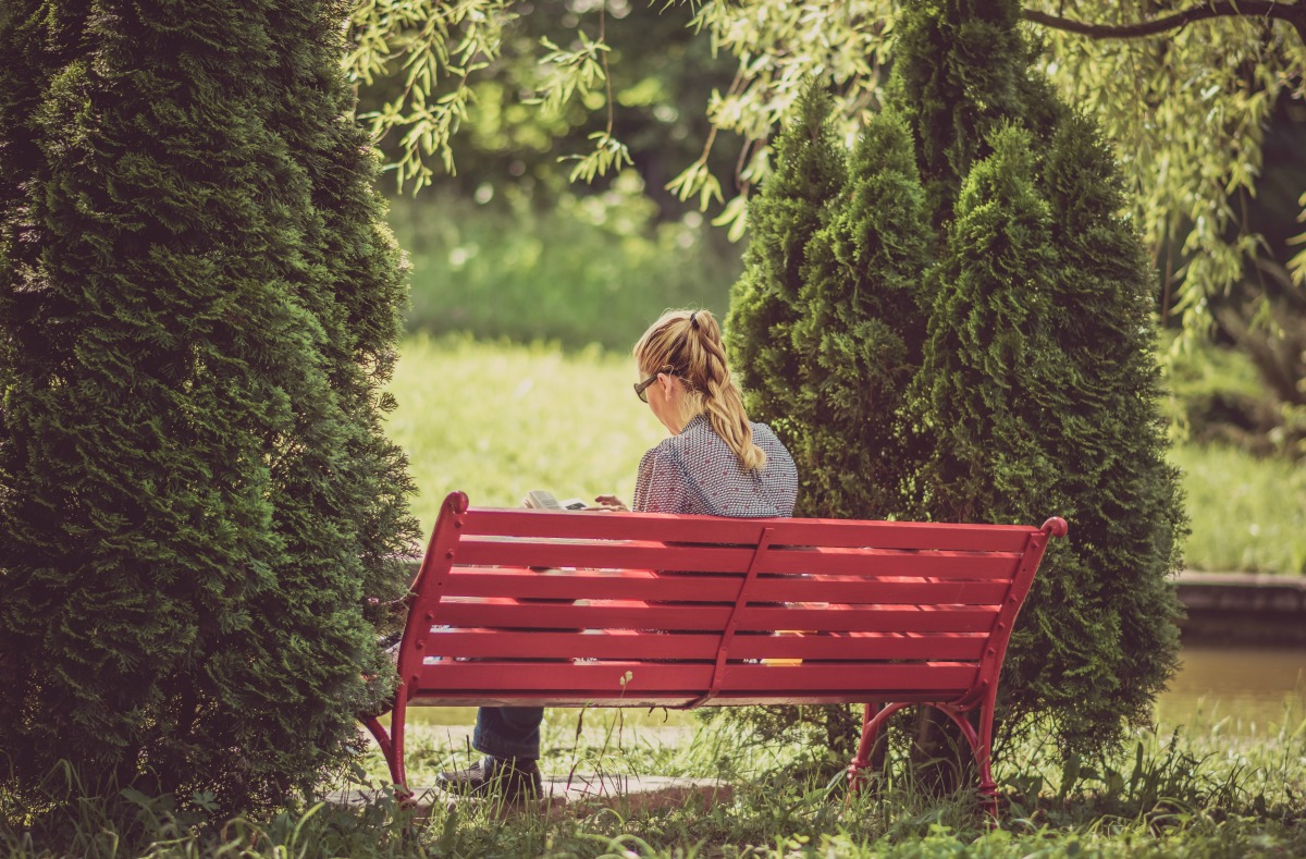 Girl sitting on a bench surrounded by trees