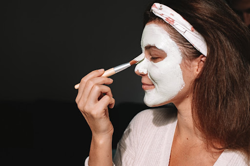 woman using a brush to apply a facemask