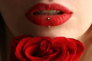 Red lips with a bar through the bottom lip above a red rose