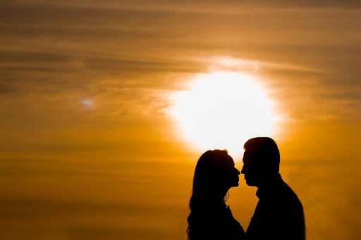 Feature image - a couple kissing in silhouette with the sunset behind them