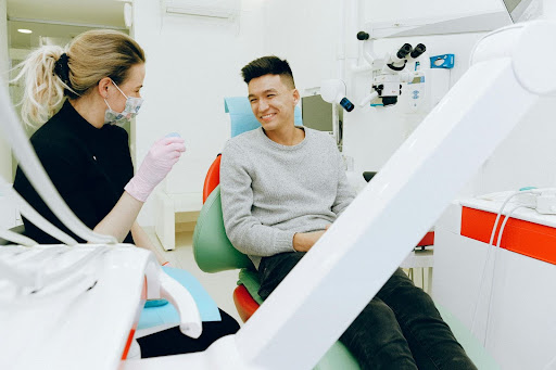A man sitting in a dentists chair talking to the dentist